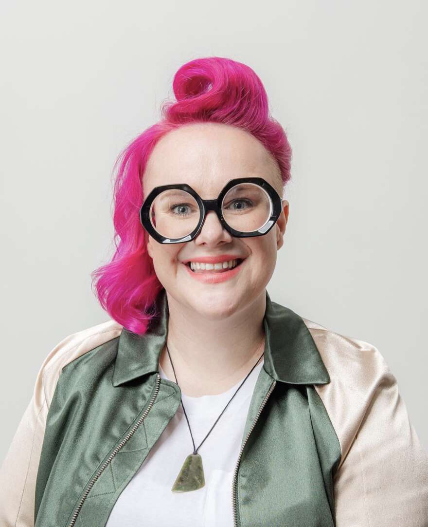 Headshot of Aych's pink hair, large glasses and leather jacket