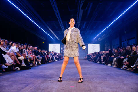 Image shows a model who lives with down syndrome strutting in a two piece suit