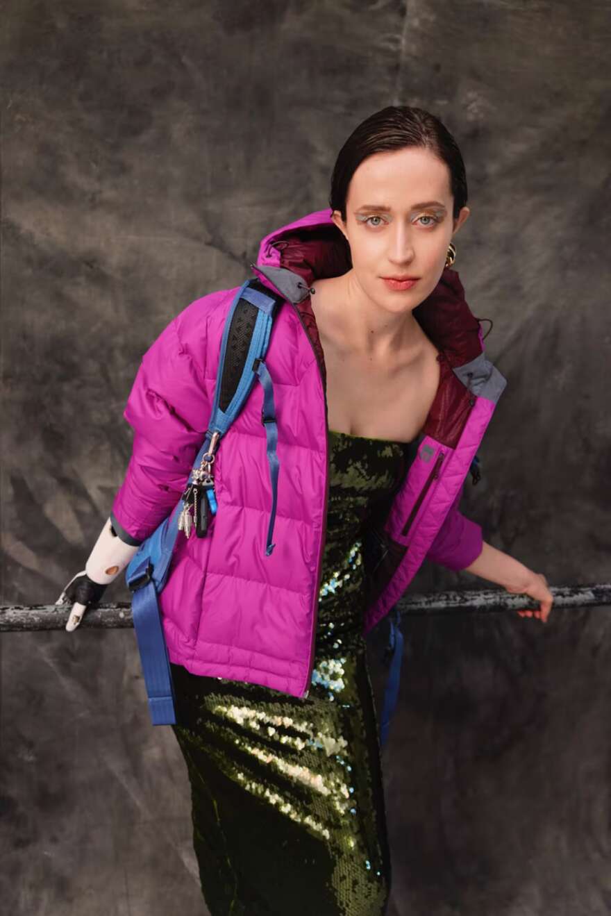 Image shows Lara, who has a limb difference, in a purple jacket and sparkling dress