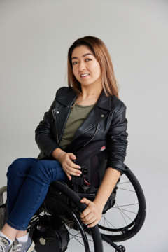 Olivia sits side on on her wheelchair in jeans