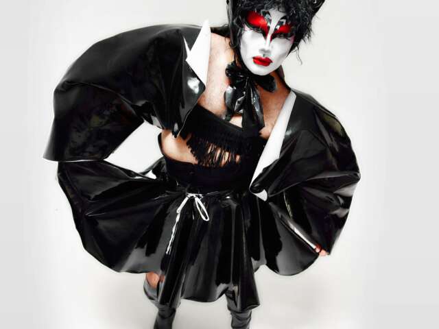 Misty is posing wearing all black with red, white, and black face paint in front of a white backdrop.