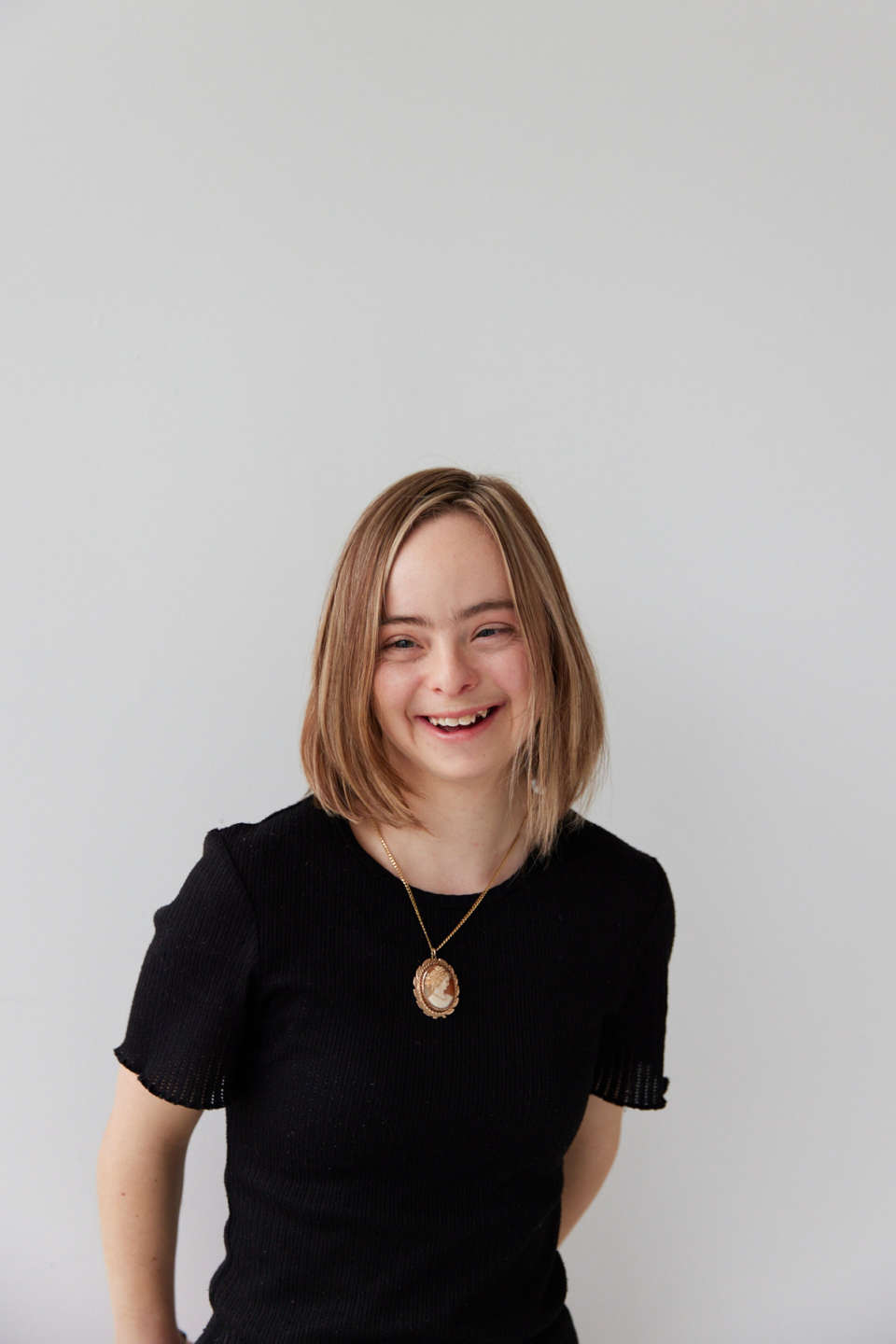 Amelia lives with down syndrome she's smiling in front of a white wall