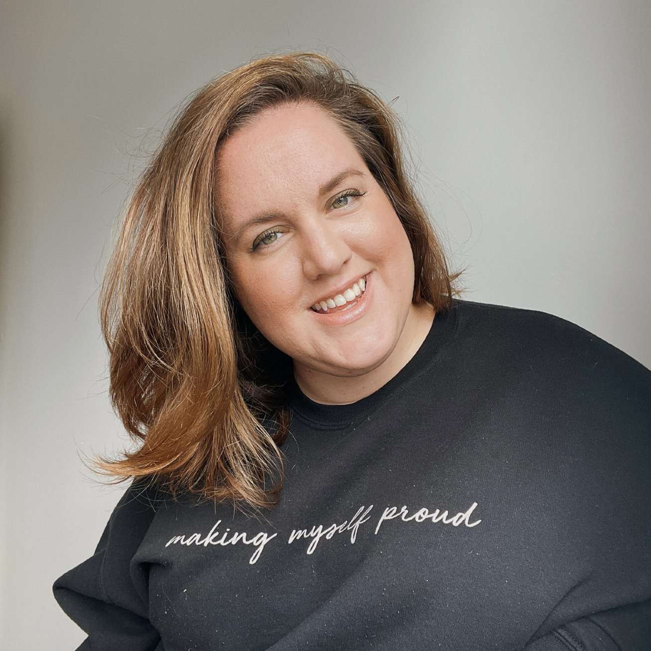 Nat is a white woman wearing a jumper that reads "Making myself proud"