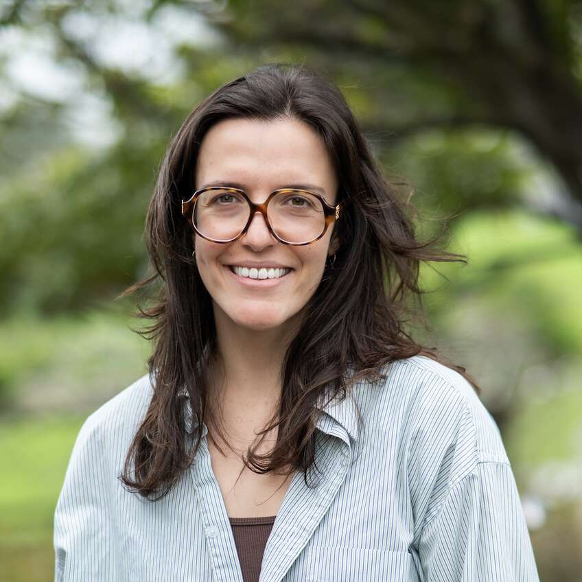 Jo has brown hair and wears large round glasses, she smiles brightly